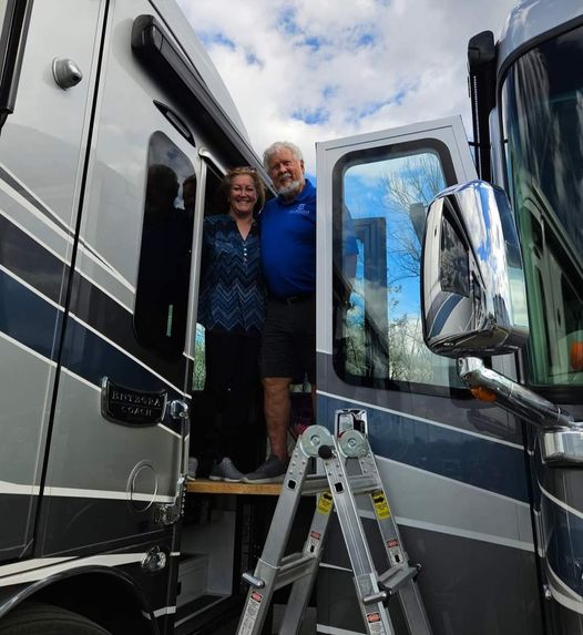 Man and woman posing between two RVs. 